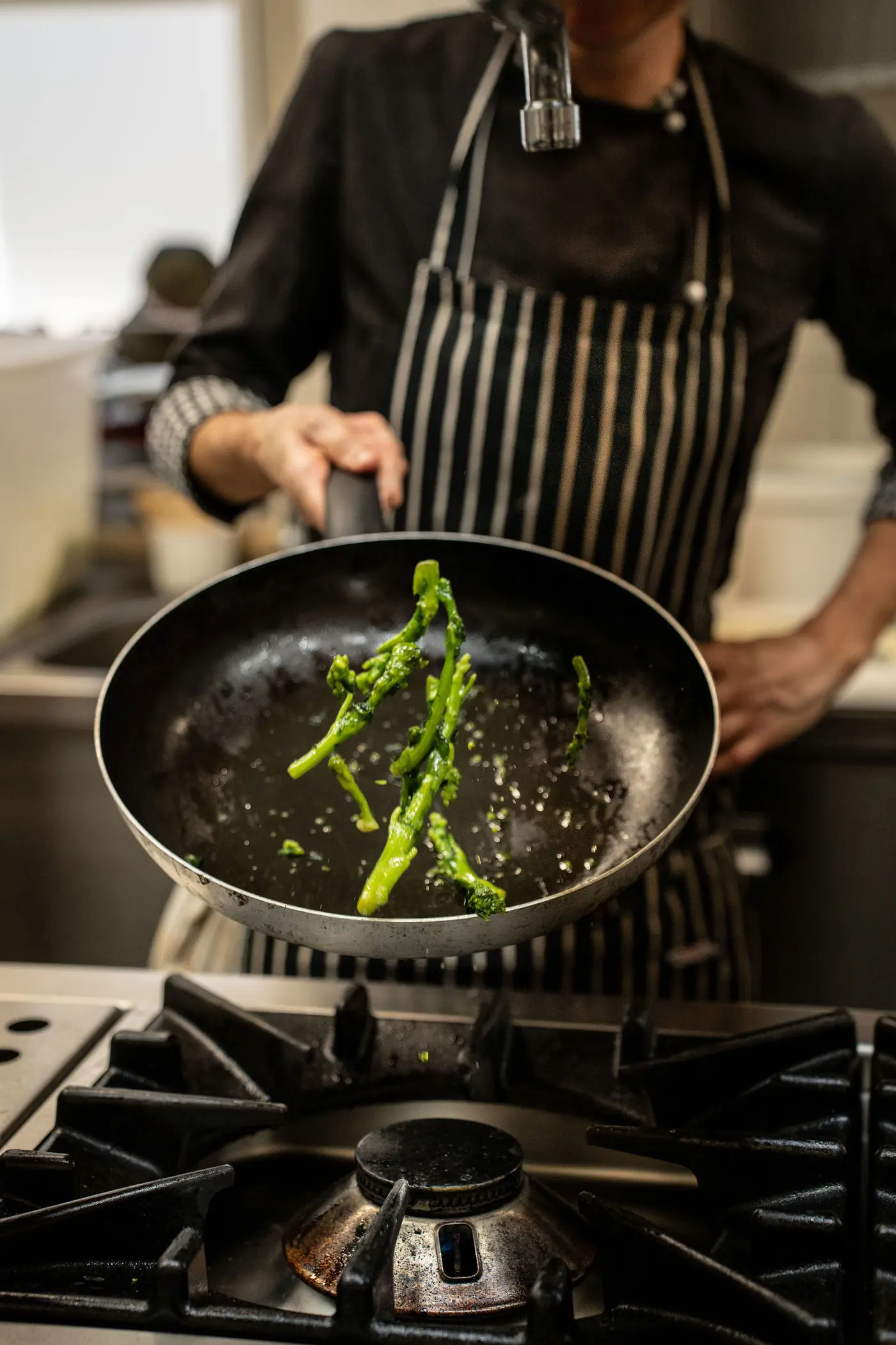 Koch schwenkt Friarielli in der Pfanne – Küche Gasthaus Rafenstein